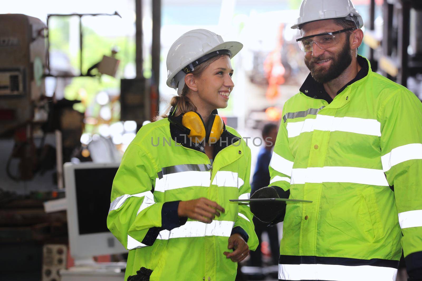 Men and female workers in factory operating machine in workshop floor.