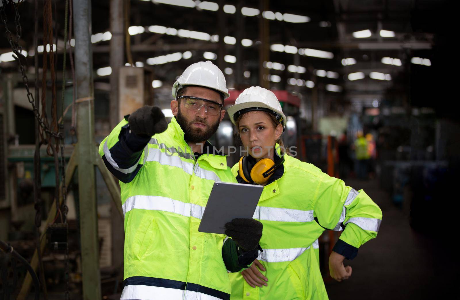 Men and female workers in factory operating machine in workshop floor.	
