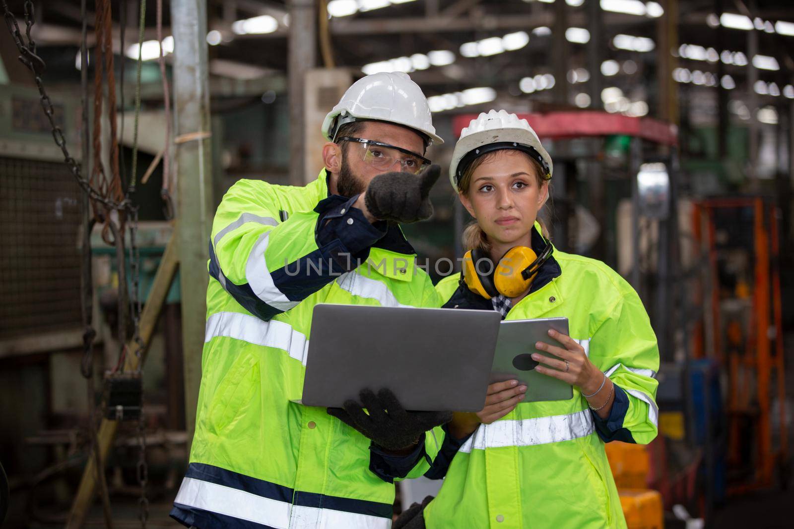 Men and female workers in factory operating machine in workshop floor.	
