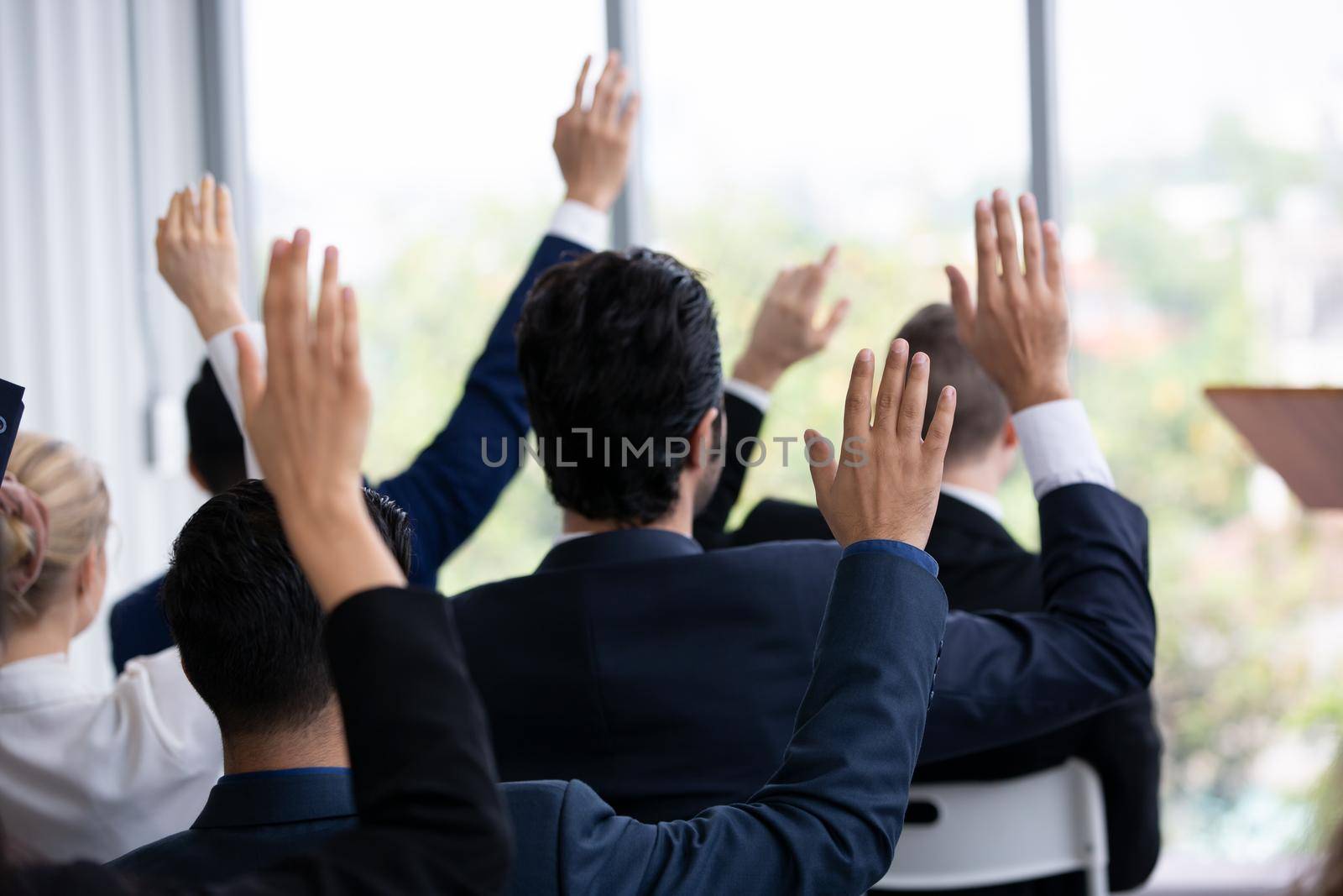 business people in seminar raising hand for vote at meeting activity or business event asking question at speaker's seminar or workshop by chuanchai