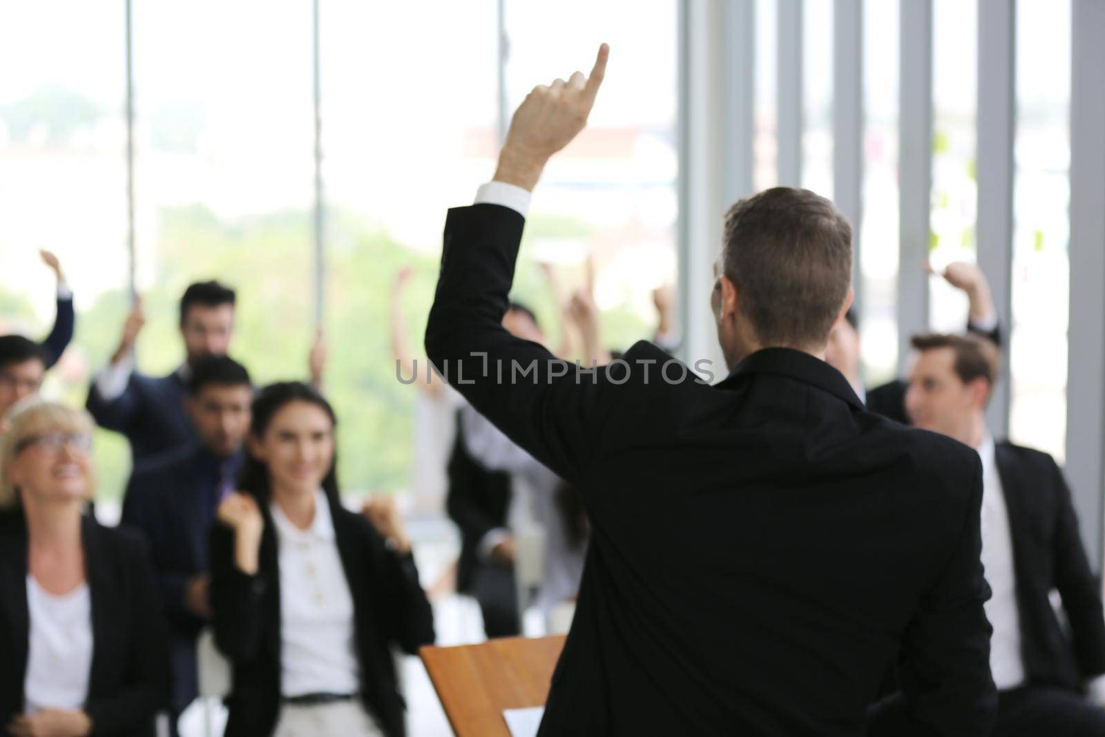 business people in seminar raising hand for vote at meeting activity or business event asking question at speaker's seminar or workshop by chuanchai