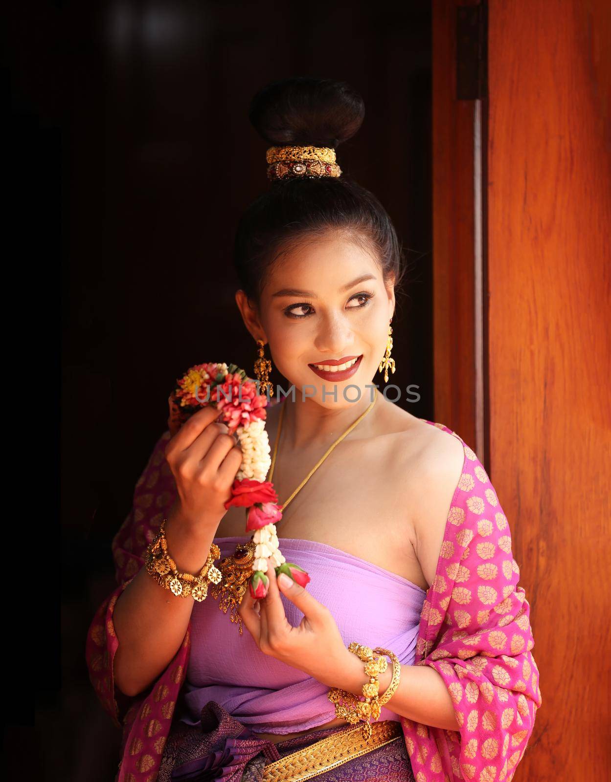 Smiling Woman In Traditional Clothing Looking Away While Standing Against Building