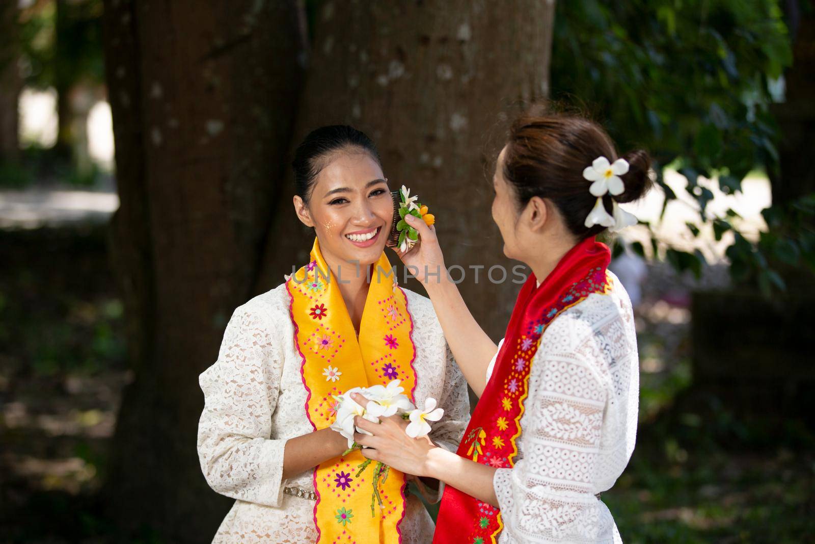 Portrait of a Two young Myanmar woman in a traditional welcoming dress and gesture with flower .