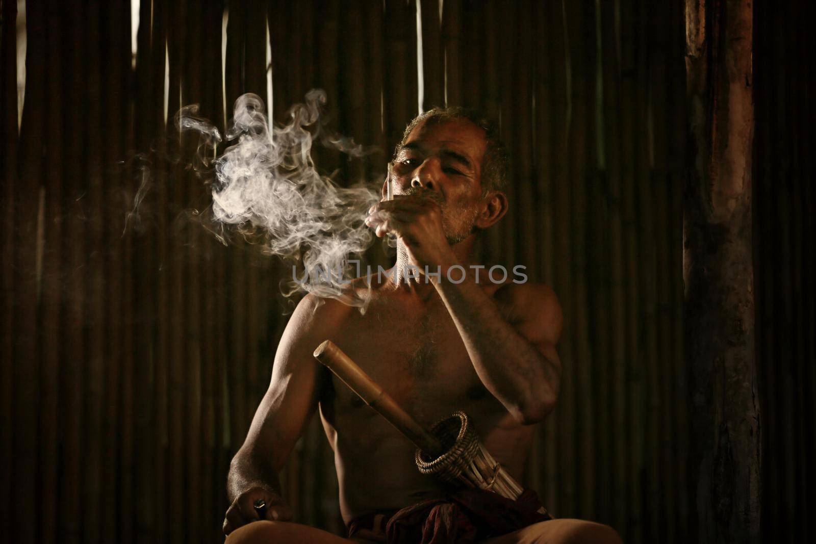 dark and sullen shot of a old man smoking over a black background