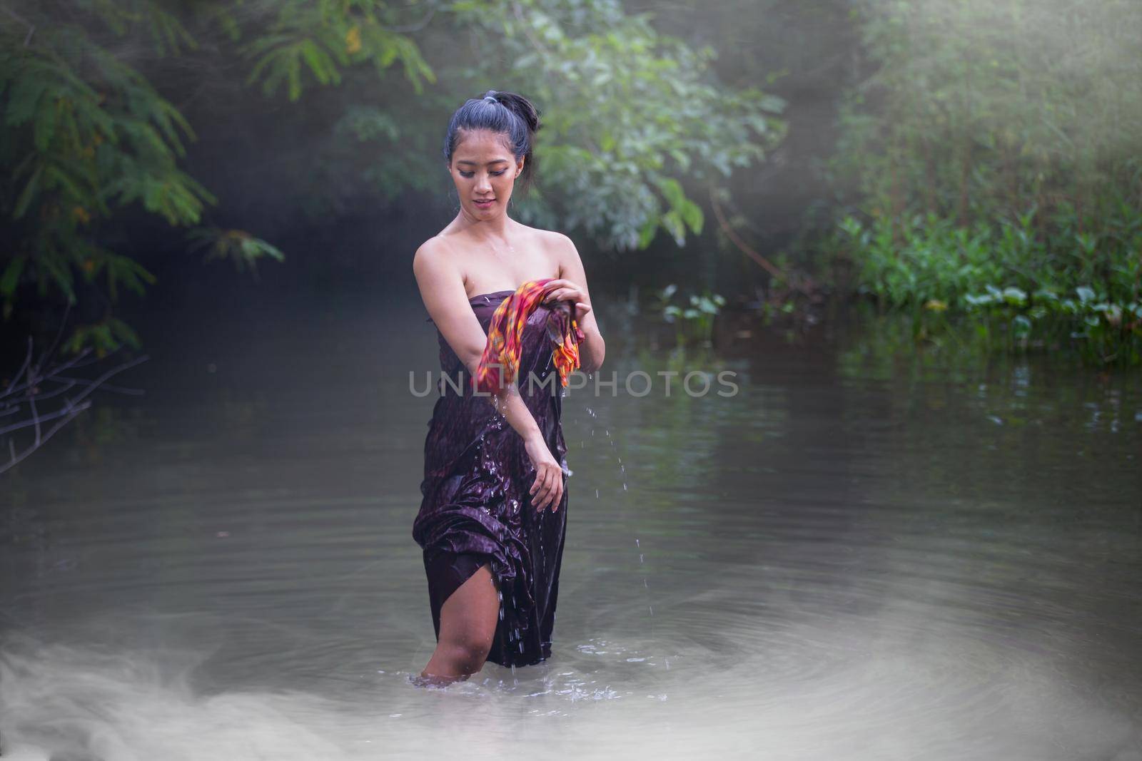 Beautiful Asian women are bathing in the river. Asia girl in Thailand. Asian girl take a shower outdoor from a traditional bamboo chute,countryside Thailand.