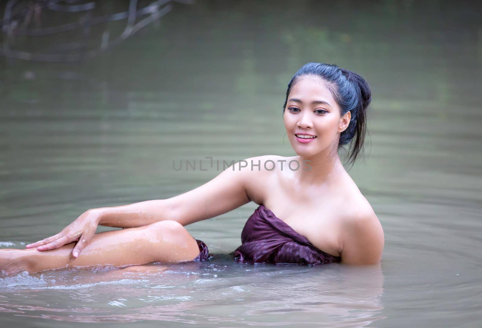 Beautiful Asian women are bathing in the river. Asia girl in Thailand. Asian girl take a shower outdoor from a traditional bamboo chute,countryside Thailand.