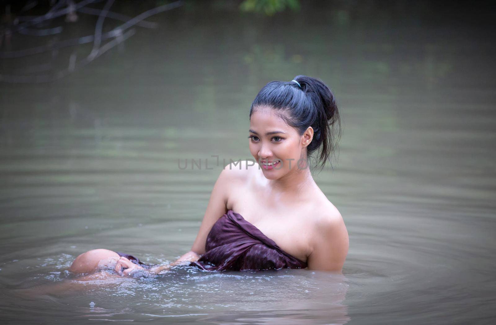 Beautiful Asian women are bathing in the river. Asia girl in Thailand. Asian girl take a shower outdoor from a traditional bamboo chute,countryside Thailand. by chuanchai