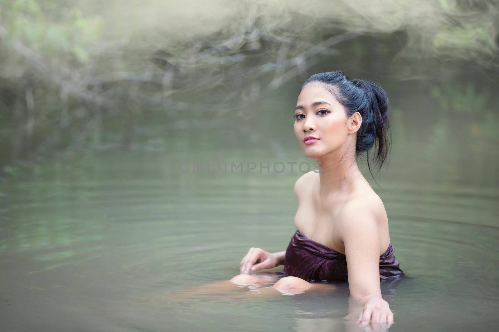 Beautiful Asian women are bathing in the river. Asia girl in Thailand. Asian girl take a shower outdoor from a traditional bamboo chute,countryside Thailand. by chuanchai