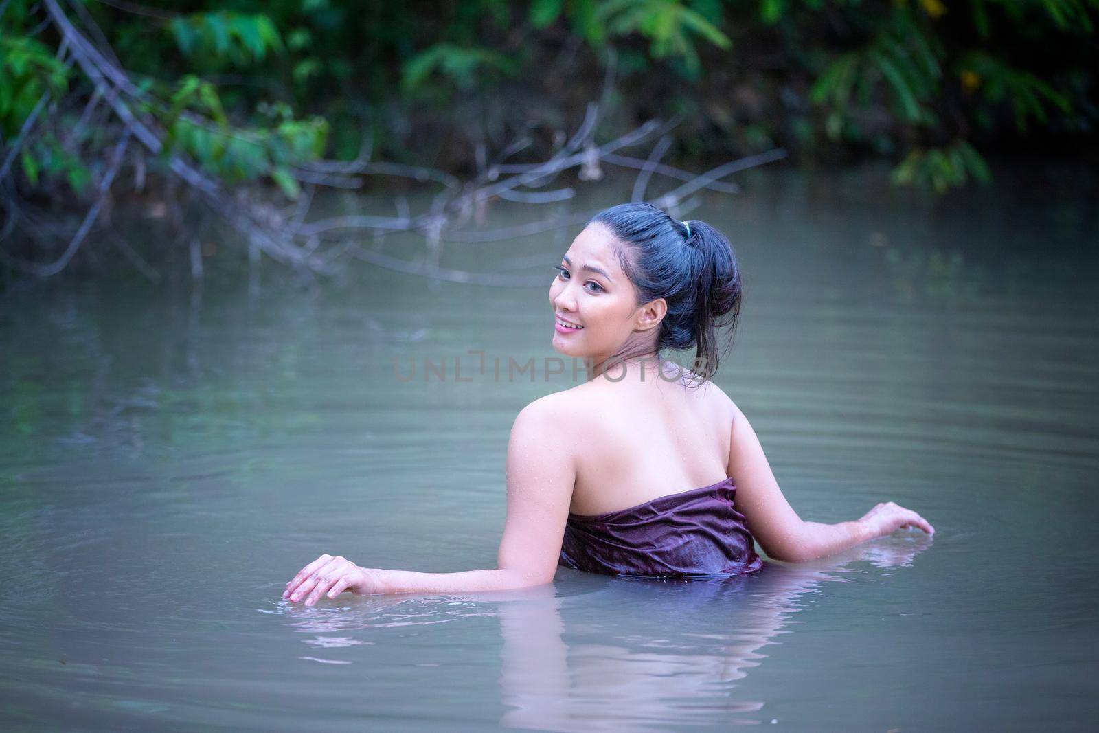 Beautiful Asian women are bathing in the river. Asia girl in Thailand. Asian girl take a shower outdoor from a traditional bamboo chute,countryside Thailand.