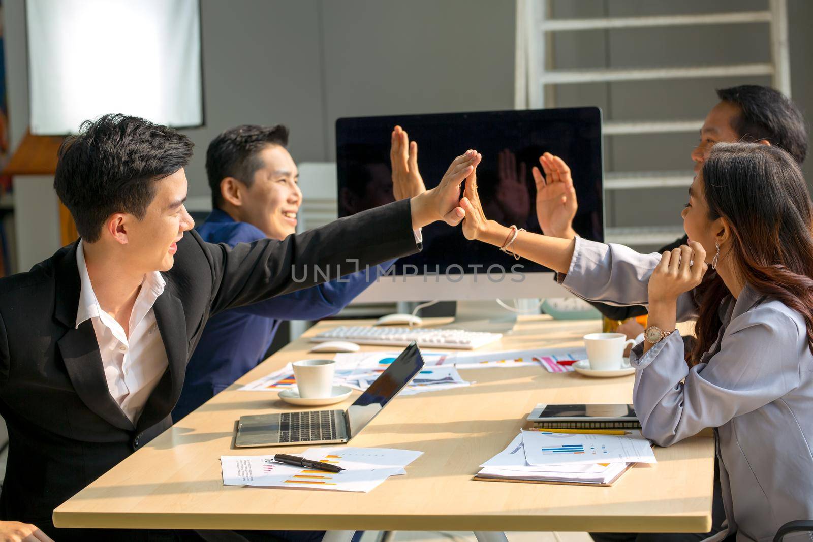 young business team working together at office. Manager pointing at a chart and explaining the analysis about business strategies. Top view shot of business hand shake