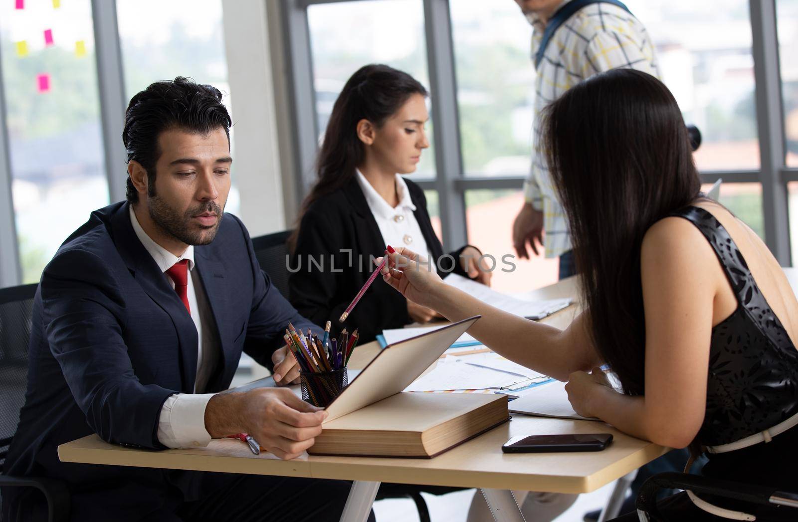 young business team working together at office. Manager pointing at a chart and explaining the analysis about business strategies. Top view shot of business hand shake