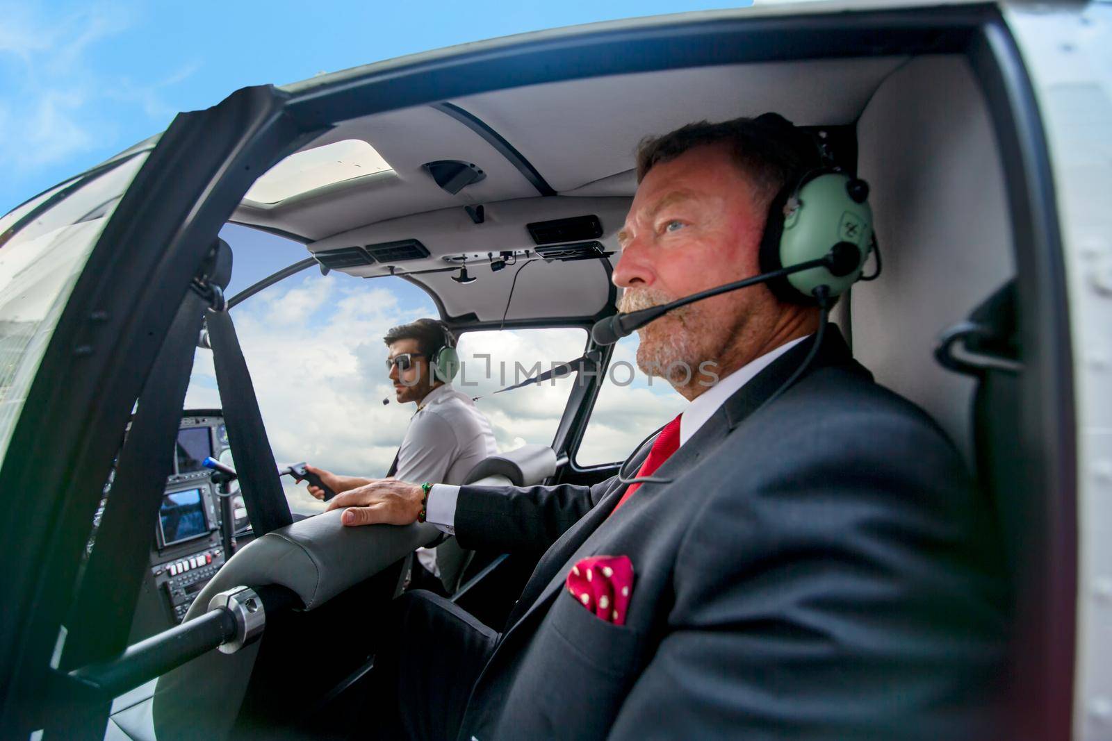 Business people traveling by helicopter , Shot of a mature businessman using a headset while traveling in a helicopter
