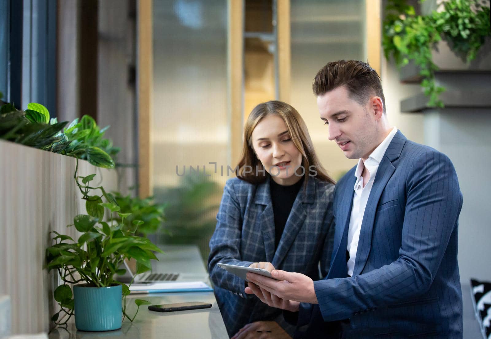 Two business people sitting at cafe working on new project using laptop. Young businesswoman taking notes and businessman working on laptop computer.