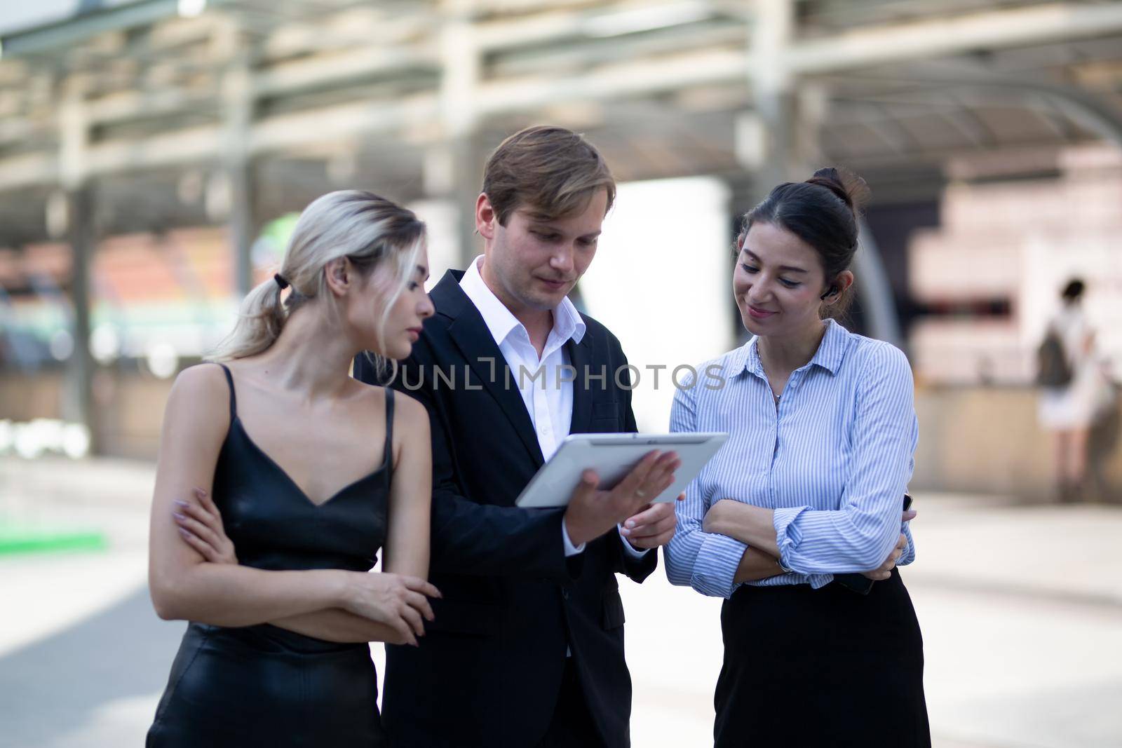 Businessman and women sitting on step outdoor looking on laptop against building