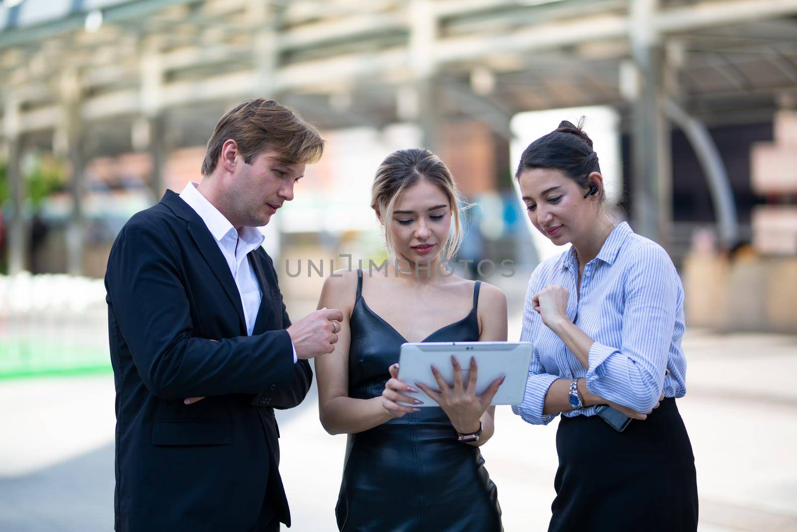 Businessman and women sitting on step outdoor looking on laptop against building by chuanchai