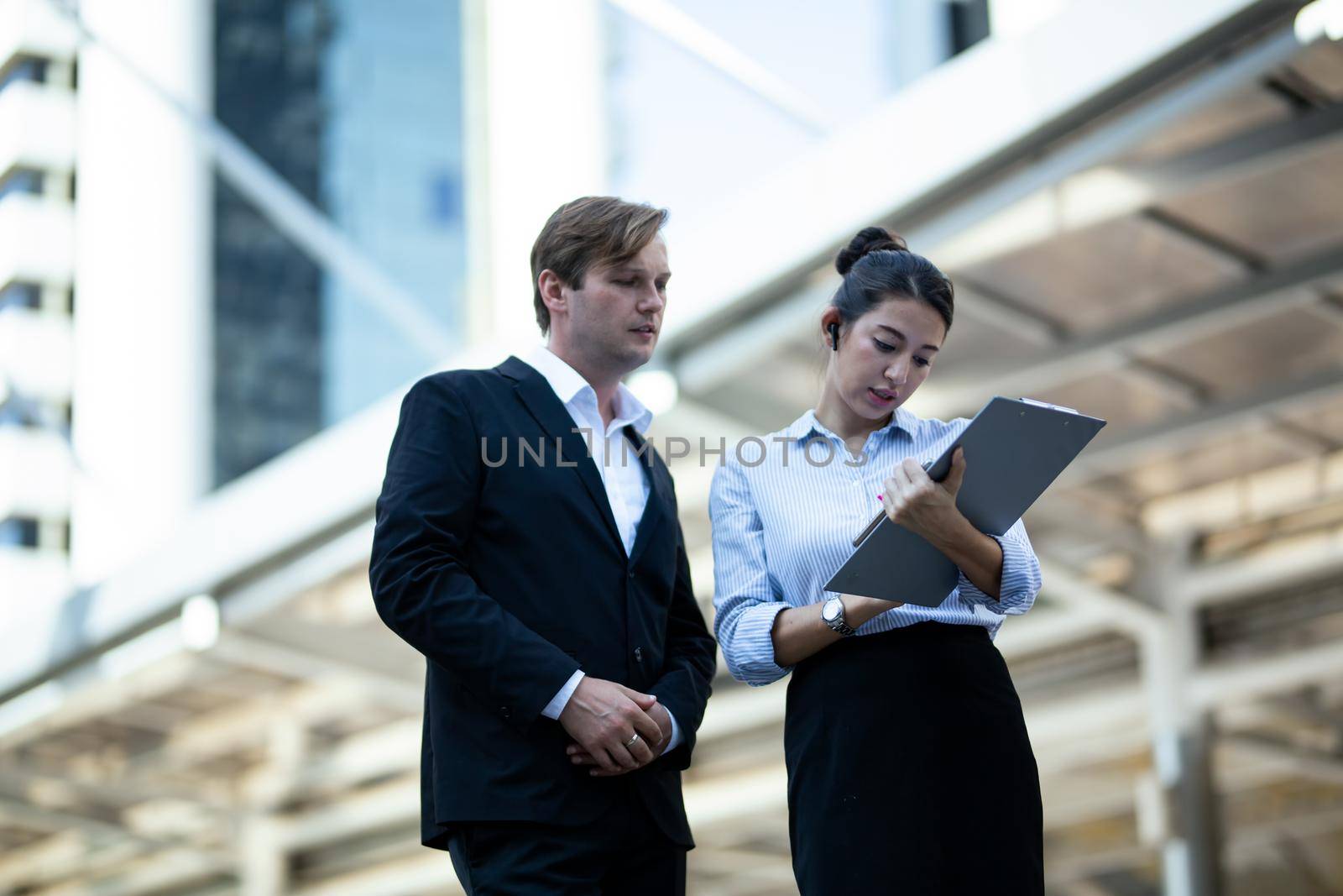 Businessman and women sitting on step outdoor looking on laptop against building by chuanchai
