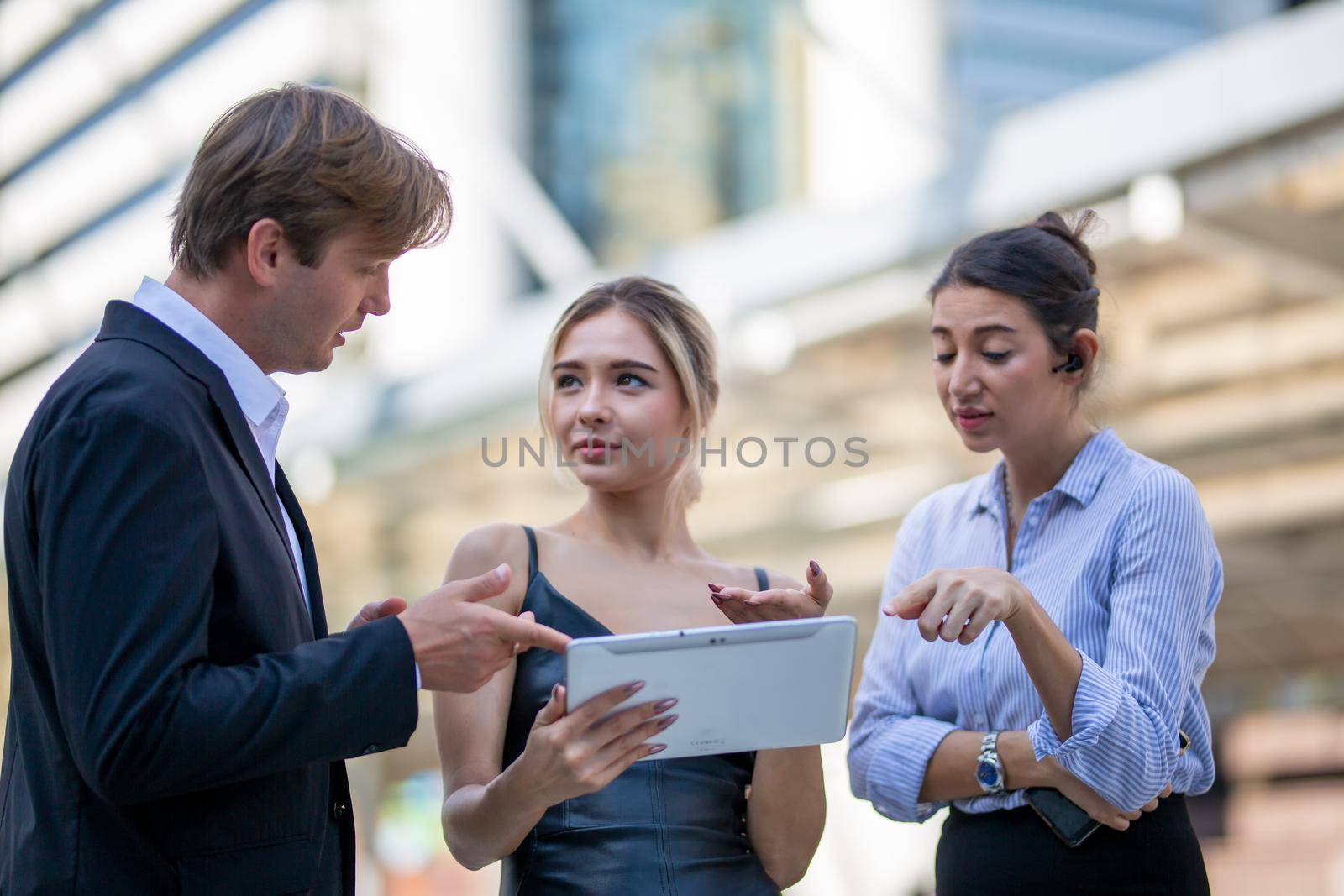 Businessman and women sitting on step outdoor looking on laptop against building