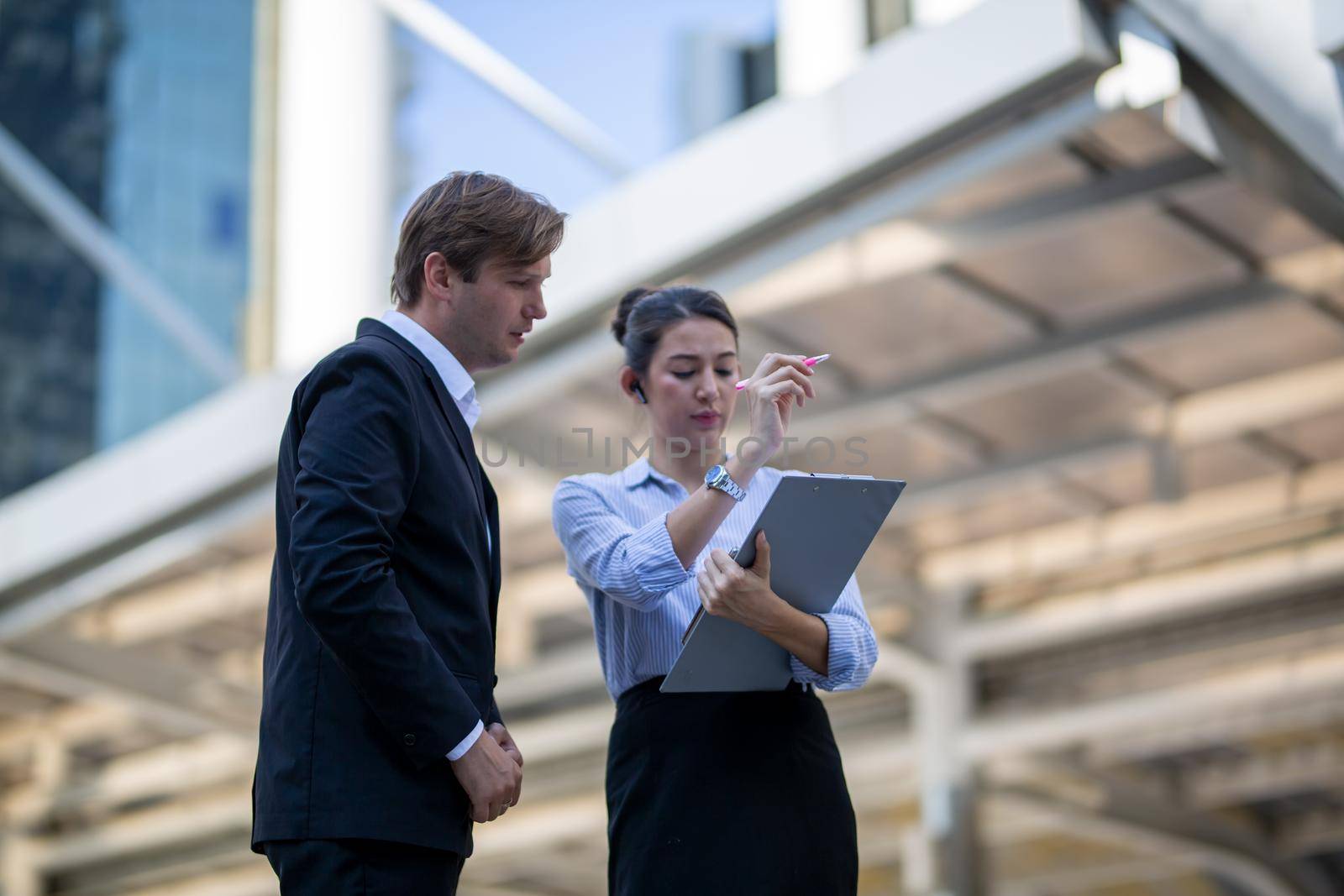 Businessman and women sitting on step outdoor looking on laptop against building by chuanchai