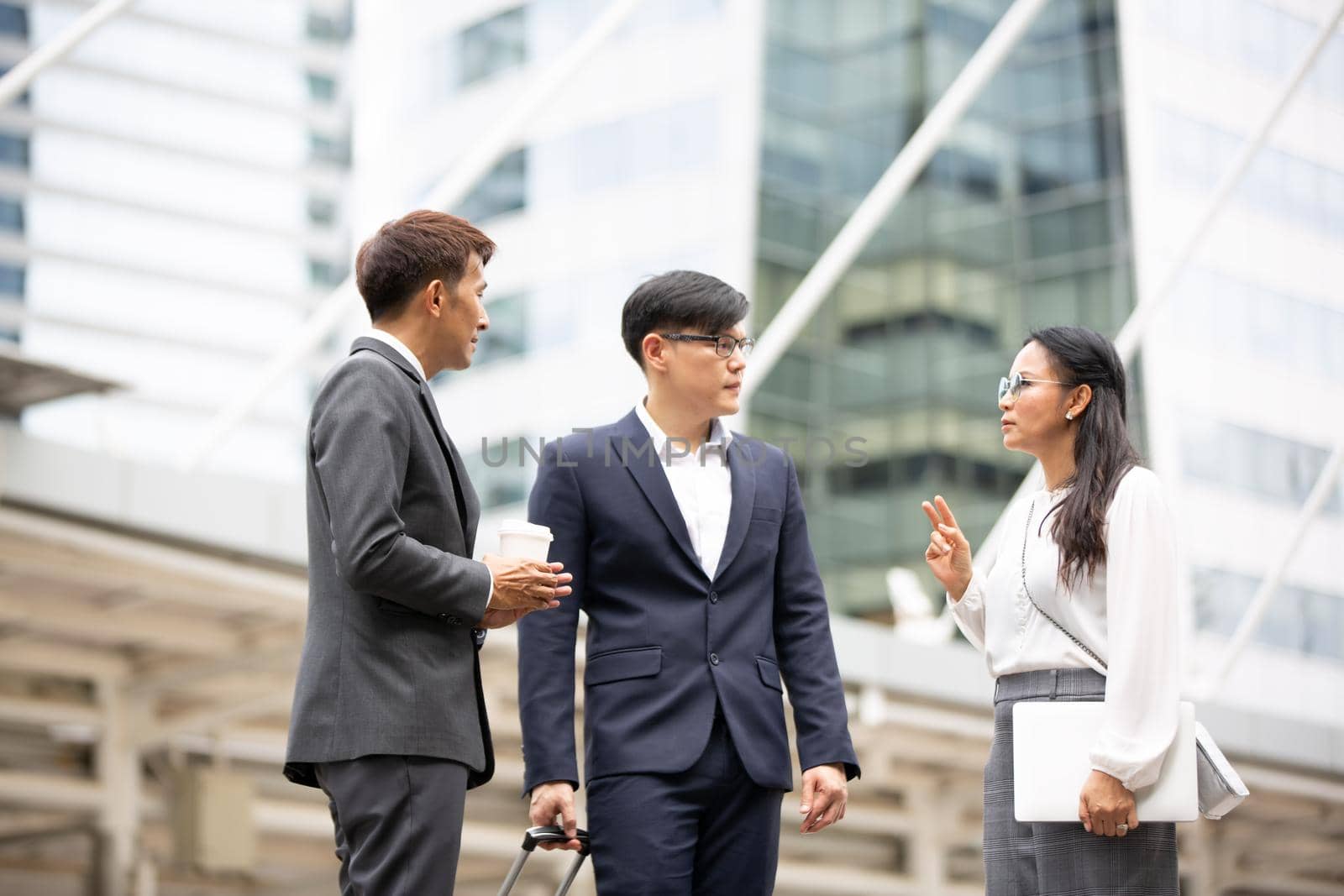 Group of business people standing with hand shaking on business agreement or teamwork against building by chuanchai