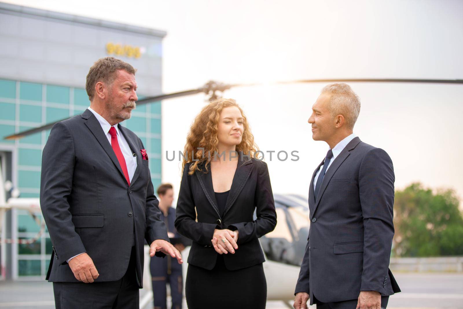 confident business people standing against his private helicopter at landing airport. Professional career success concept	