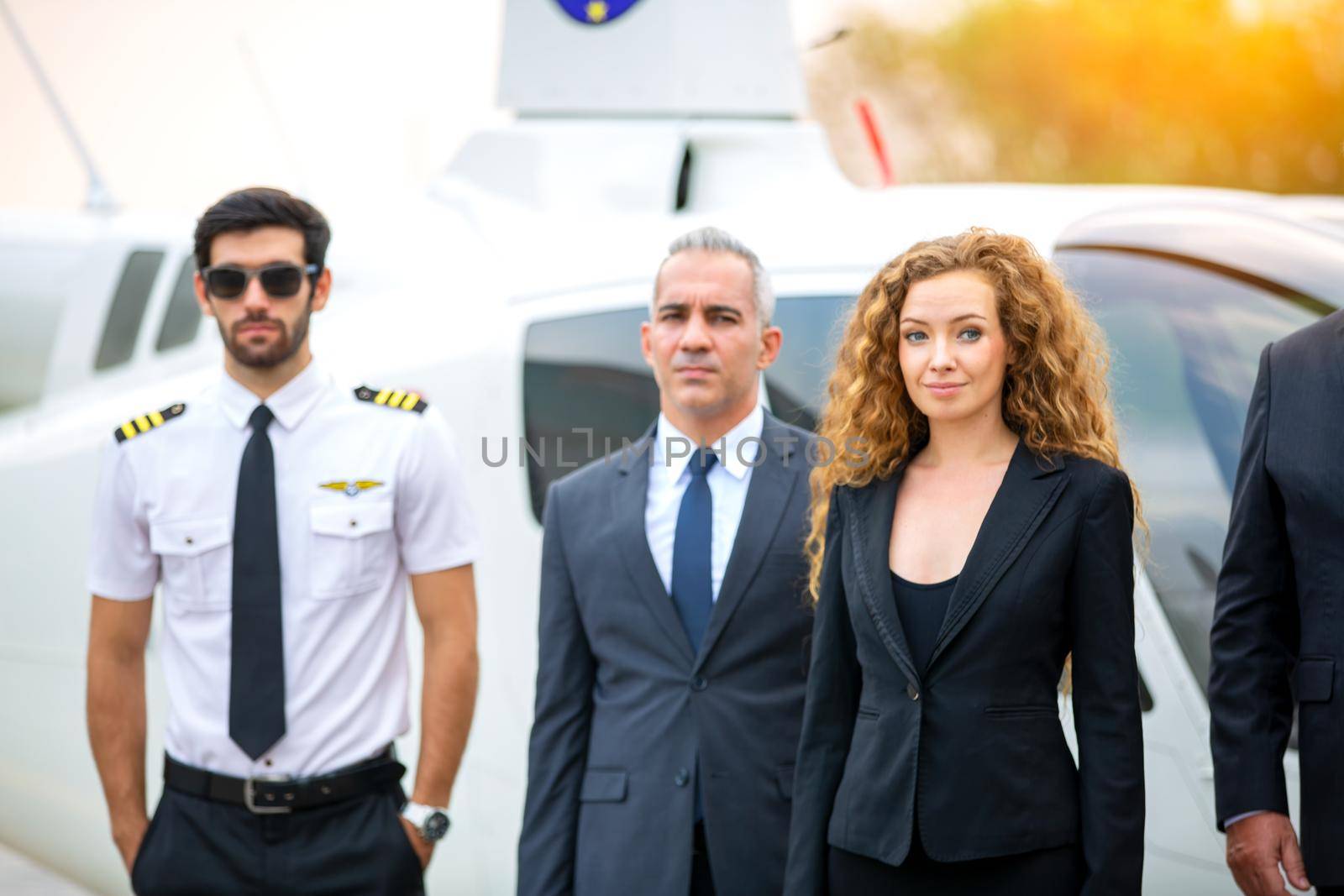 Close up of a male helicopter pilot wear sun glass and business people or executive CEO standing against helicopter at aircraft landing point in airport on a bright sunny day. by chuanchai