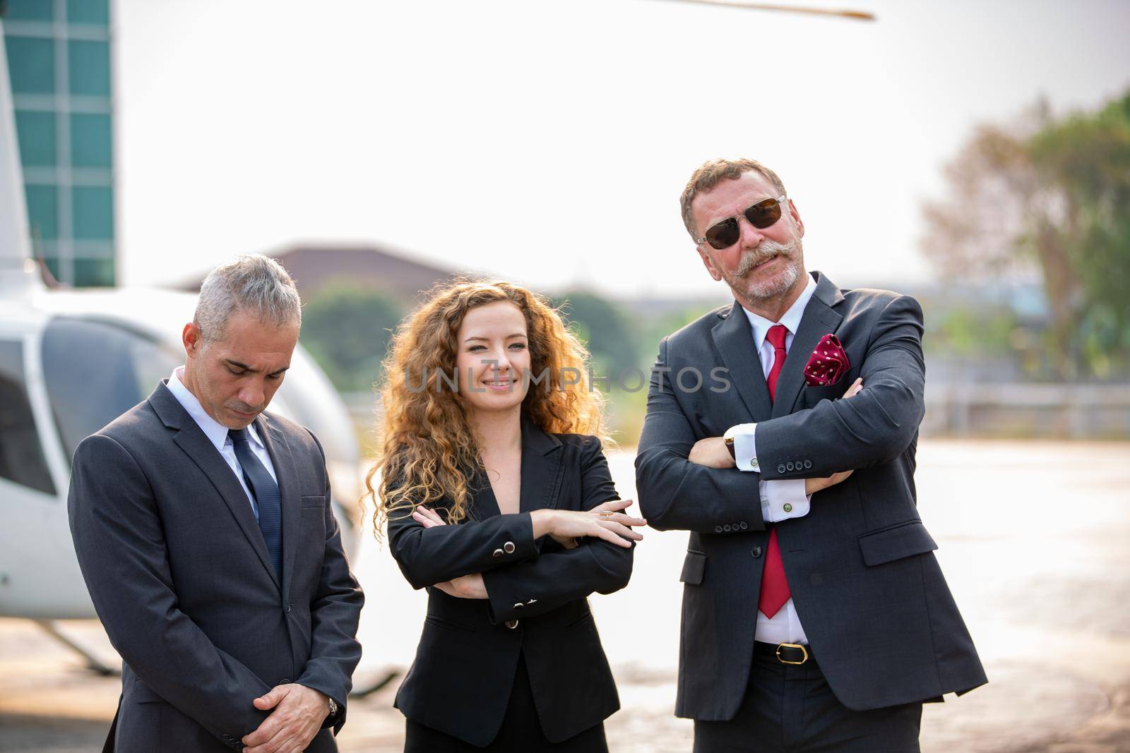 Close up of a male helicopter pilot wear sun glass and business people or executive CEO standing against helicopter at aircraft landing point in airport on a bright sunny day. by chuanchai