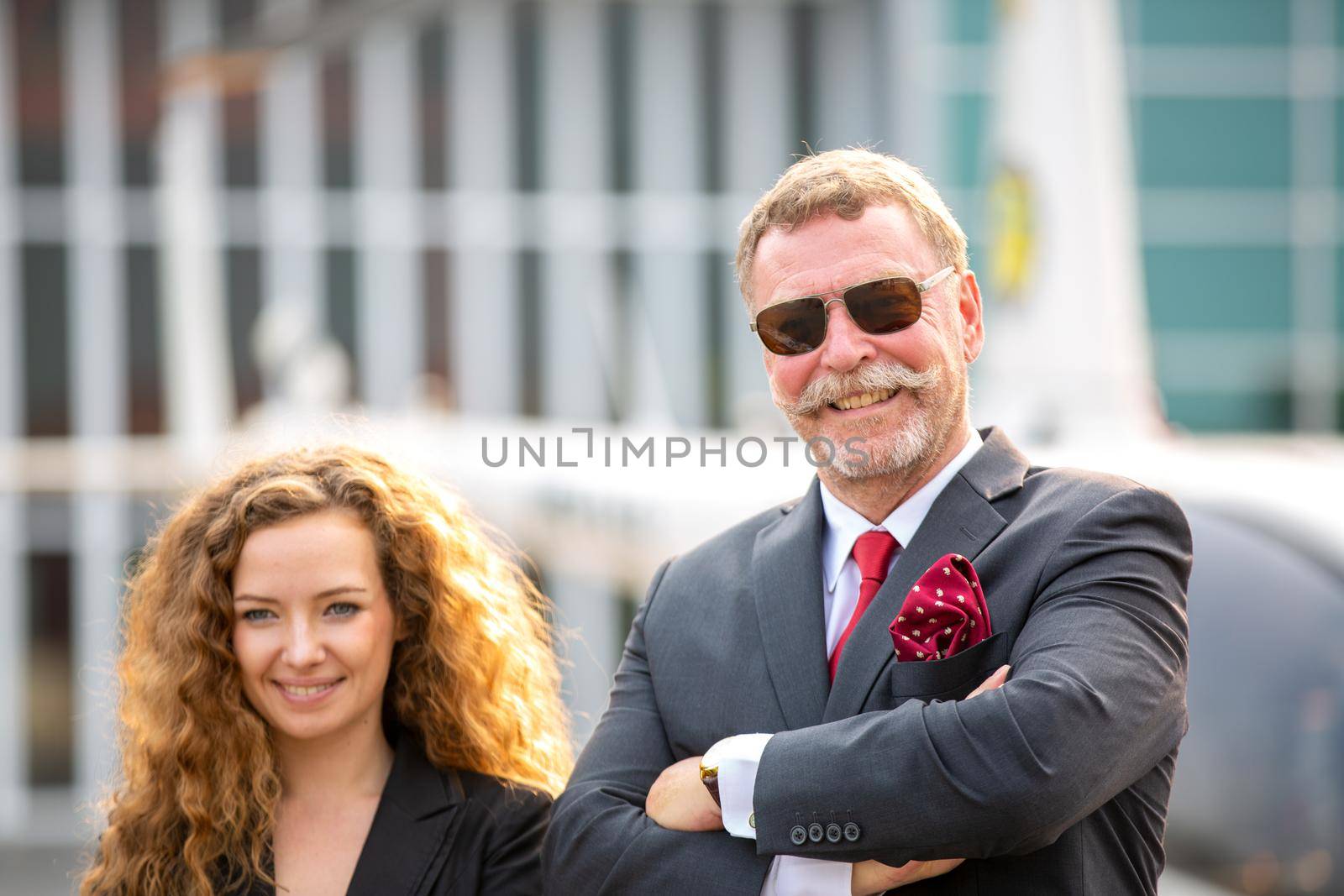 Close up of a male helicopter pilot wear sun glass and business people or executive CEO standing against helicopter at aircraft landing point in airport on a bright sunny day. by chuanchai