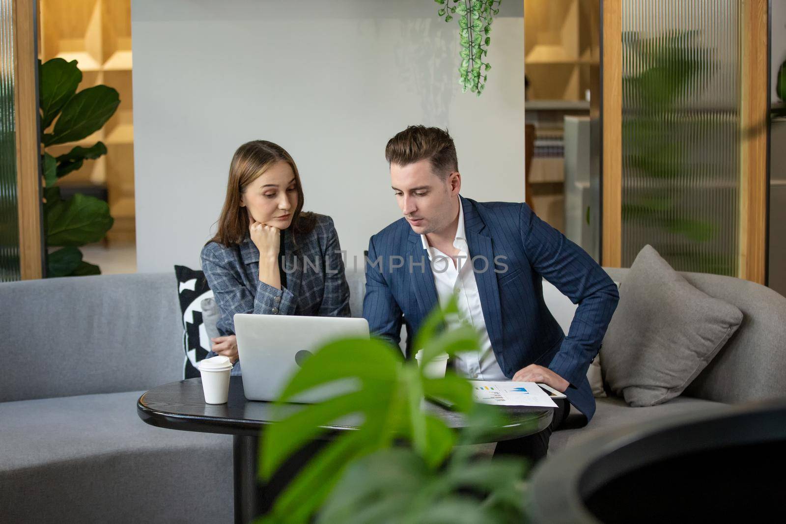 Two Cheerful Young Businessmen Using Laptop On Business Meeting Together