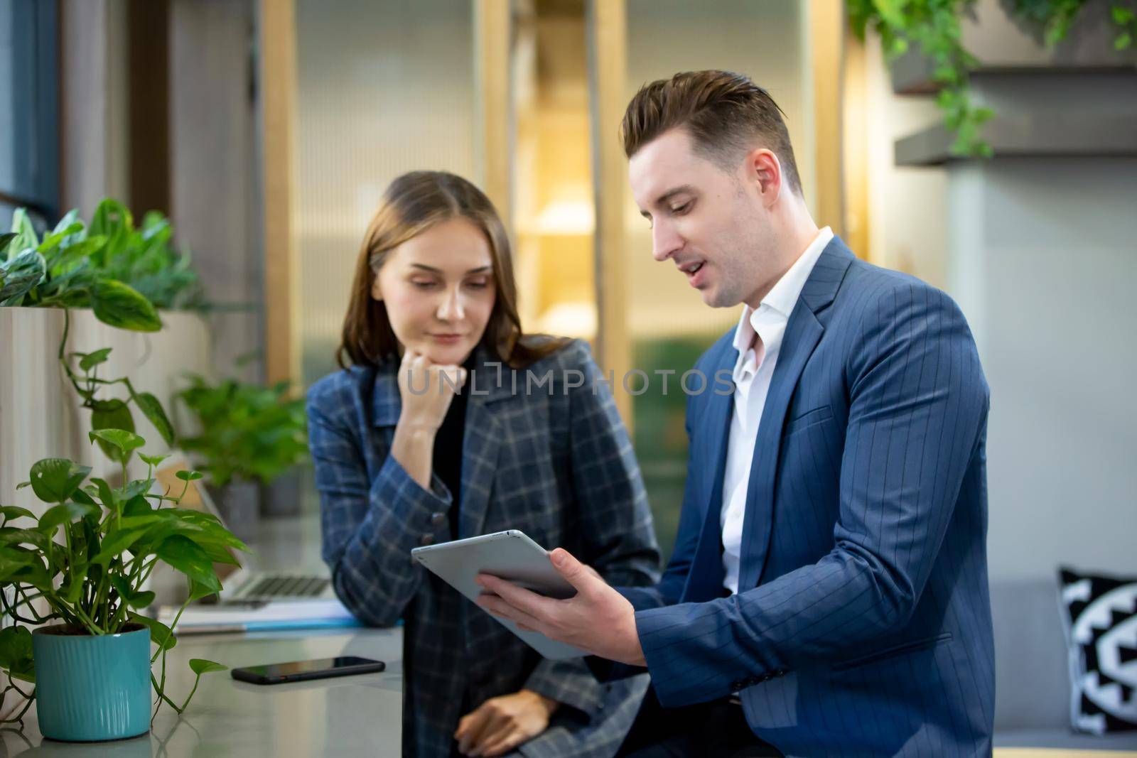 Two Cheerful Young Businessmen Using Laptop On Business Meeting Together by chuanchai