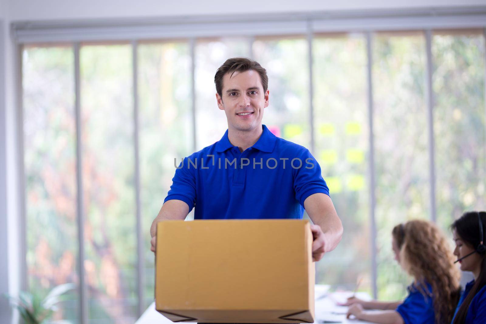 delivery man blue t-shirt holding box in call center office