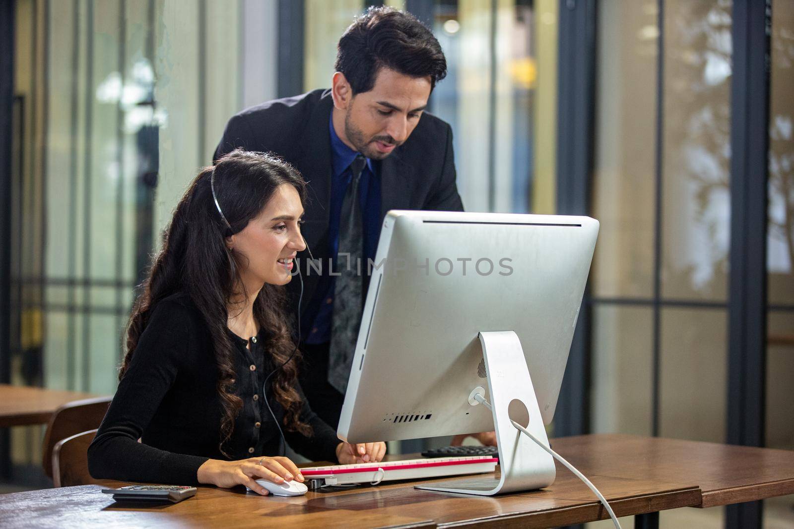 Smiling customer support operator with hands-free headset working in the office.