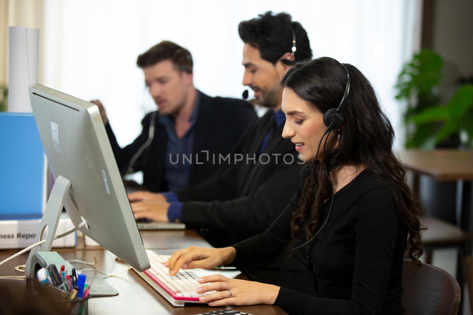 Smiling customer support operator with hands-free headset working in the office. by chuanchai