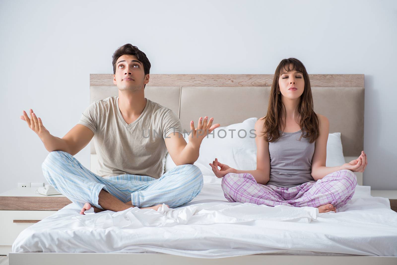 Young family meditating in the bed bedroom by Elnur