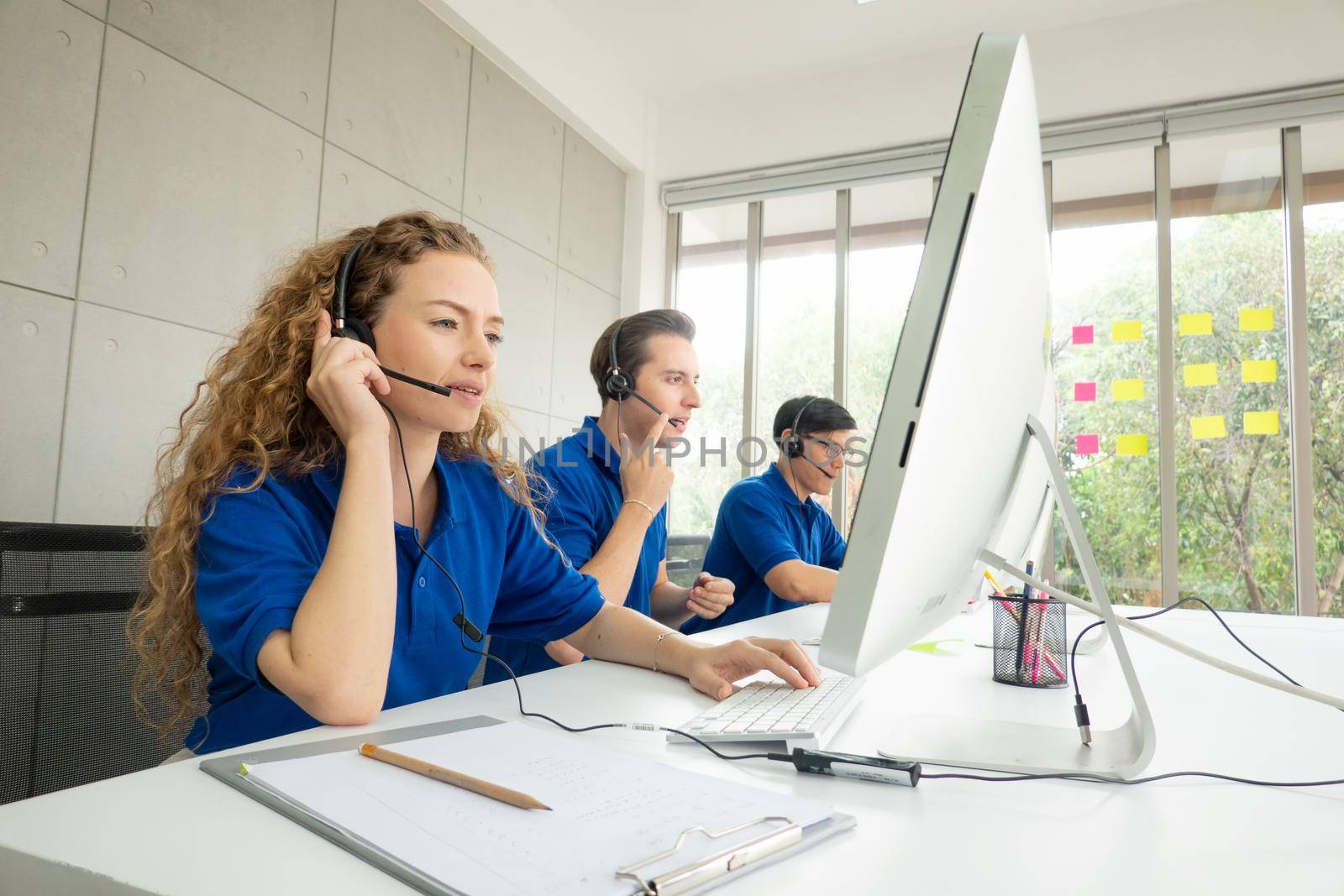 Call center team at the office. Call center operator in headset while consulting client. Telemarketing or phone sales. Customer service and business concept.