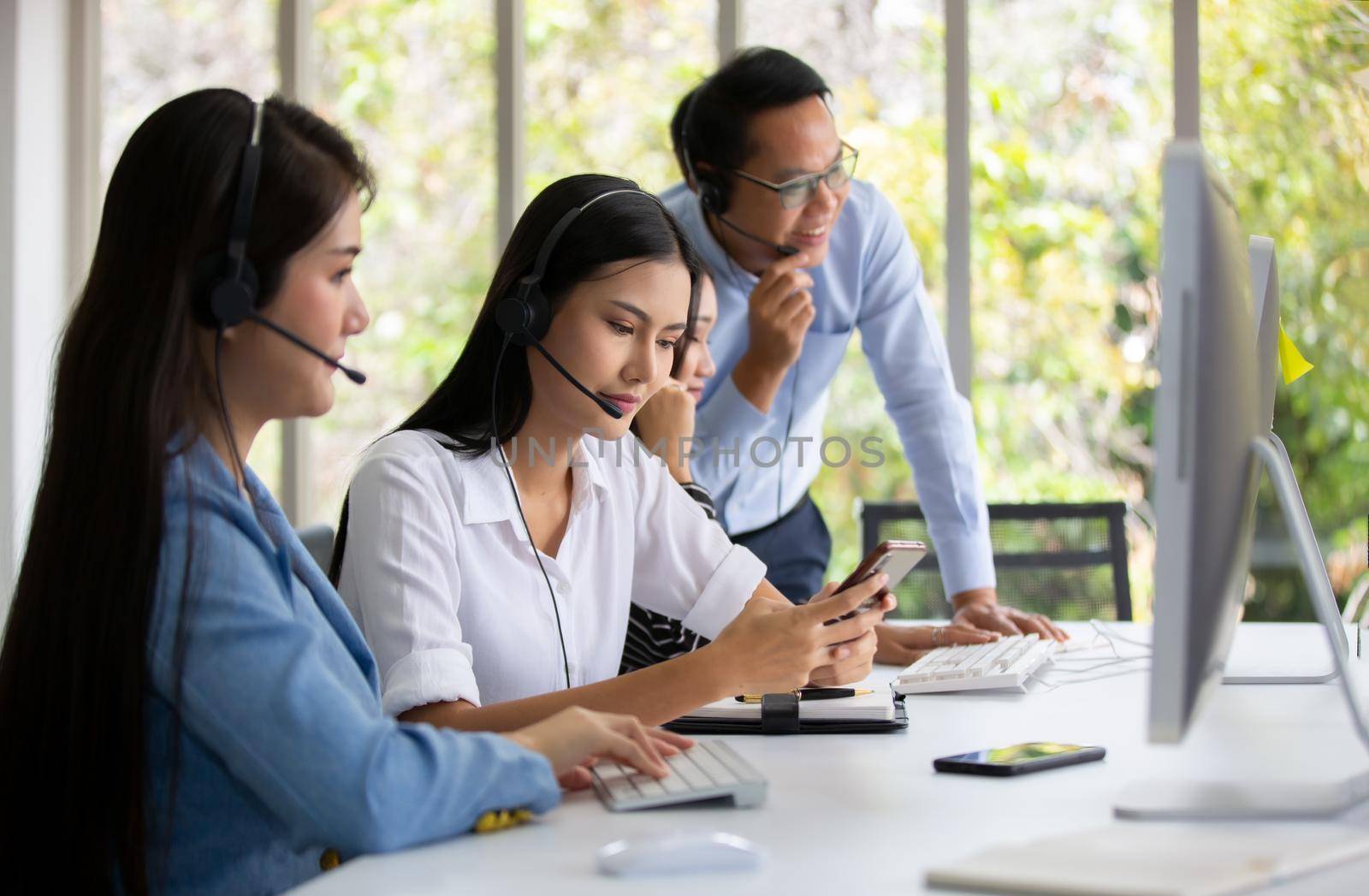 Call center operator in headset while consulting client. Telemarketing or phone sales. Customer service and business concept. by chuanchai