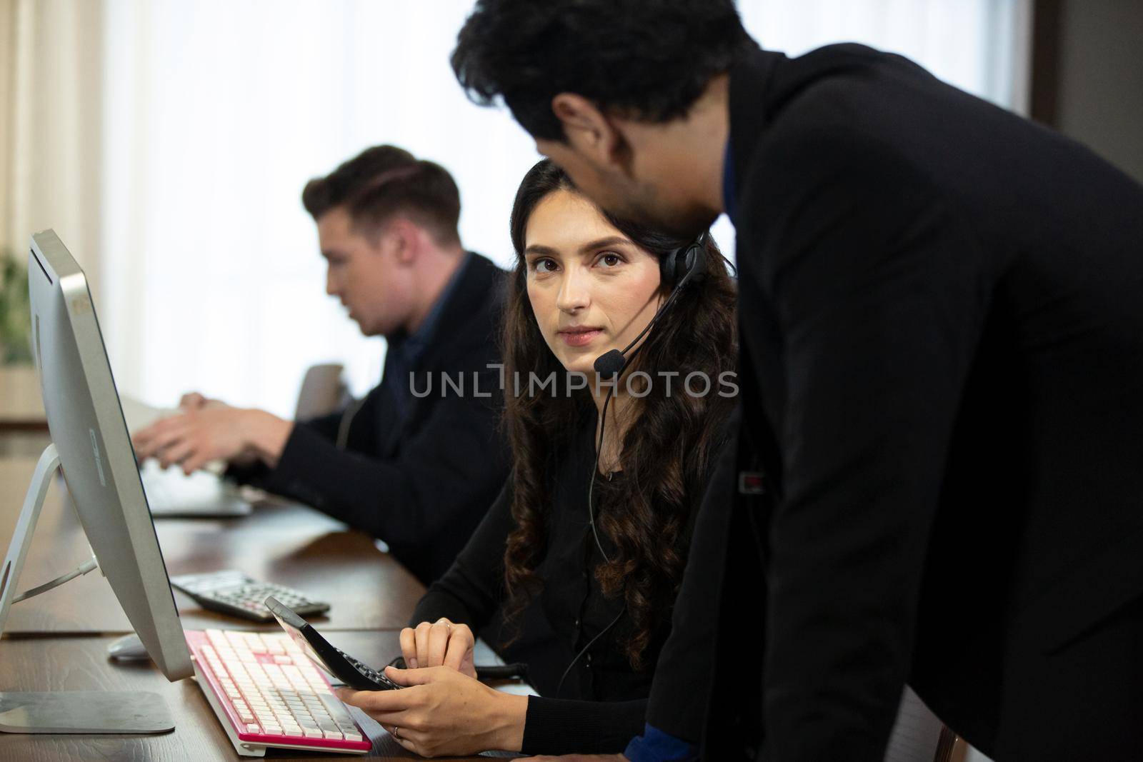 Smiling customer support operator with hands-free headset working in the office.