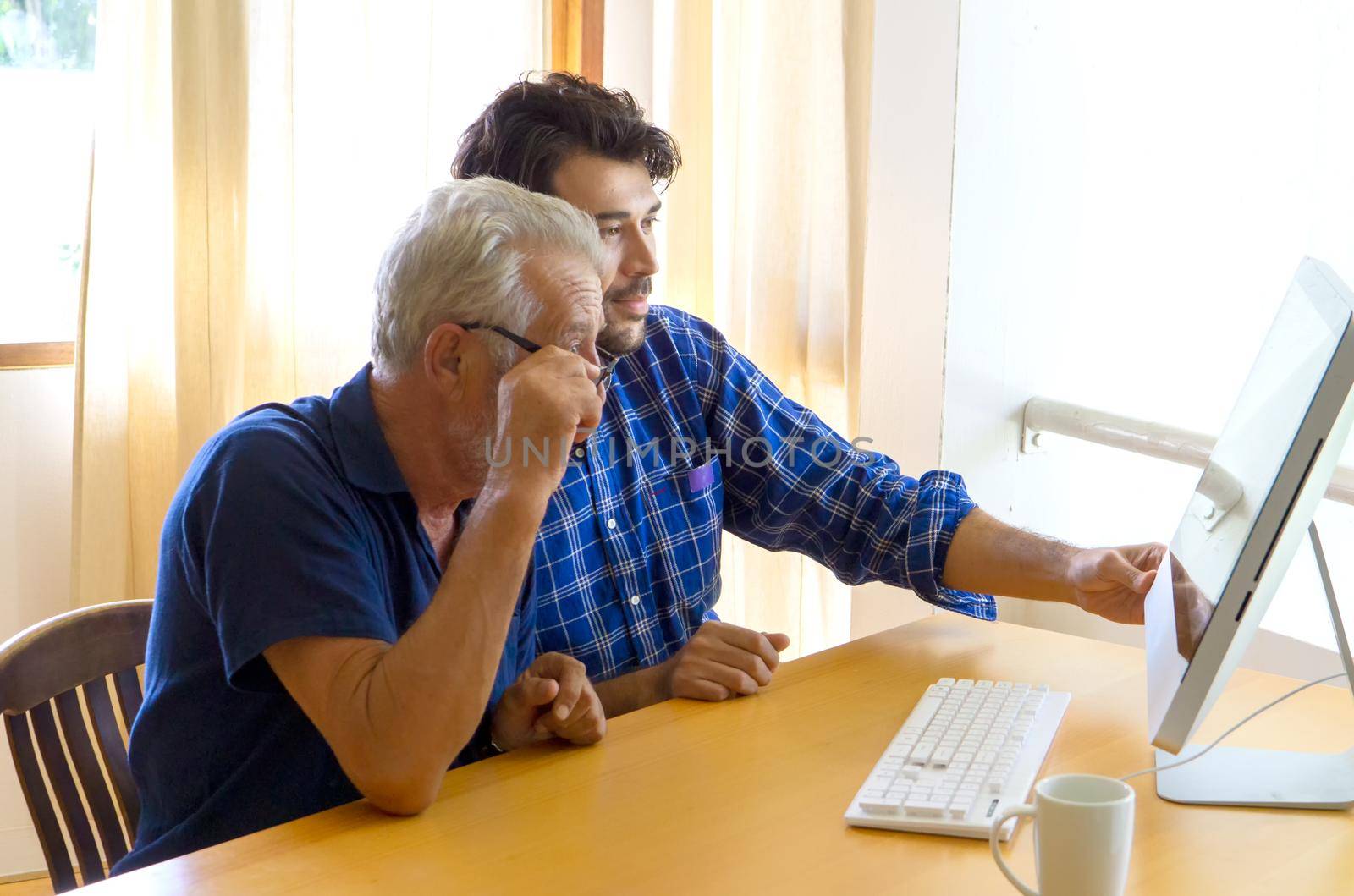 man teaching elderly man to using computer