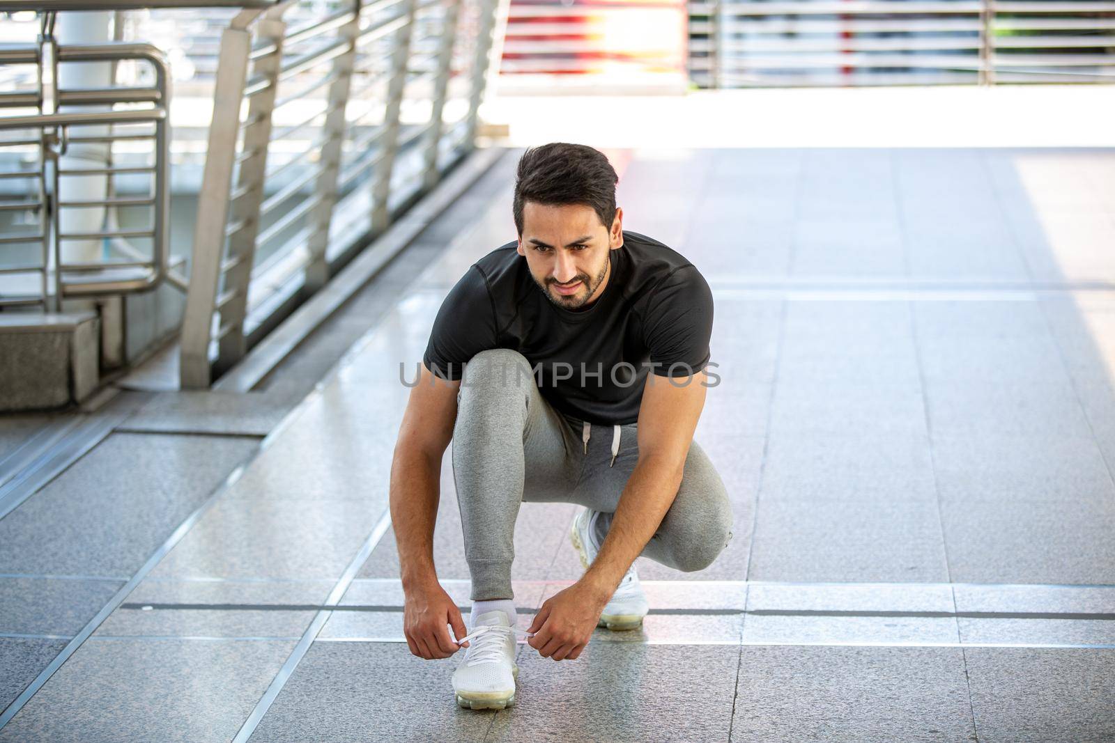 fitness, sport, exercising and lifestyle concept - Two man mix-race in sportswear sitting on relax and stretching leg on step of stadium