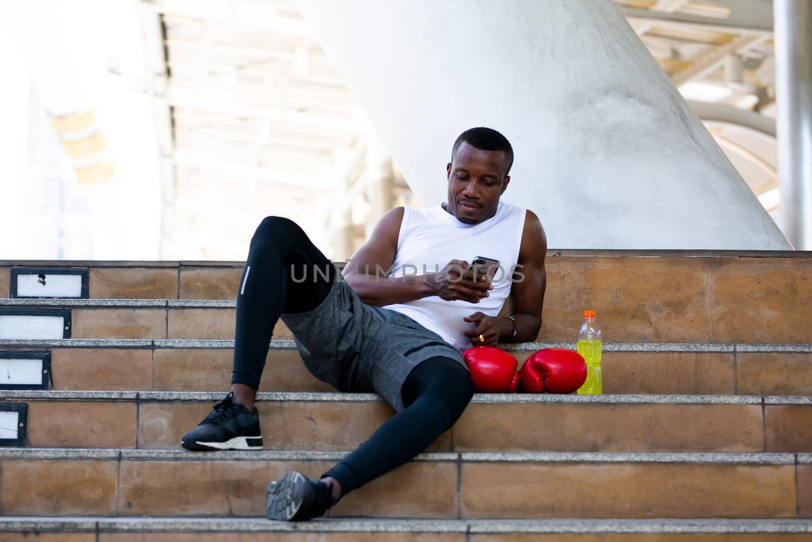 fitness, sport, exercising and lifestyle concept - Two man mix-race in sportswear sitting on relax and stretching leg on step of stadium by chuanchai