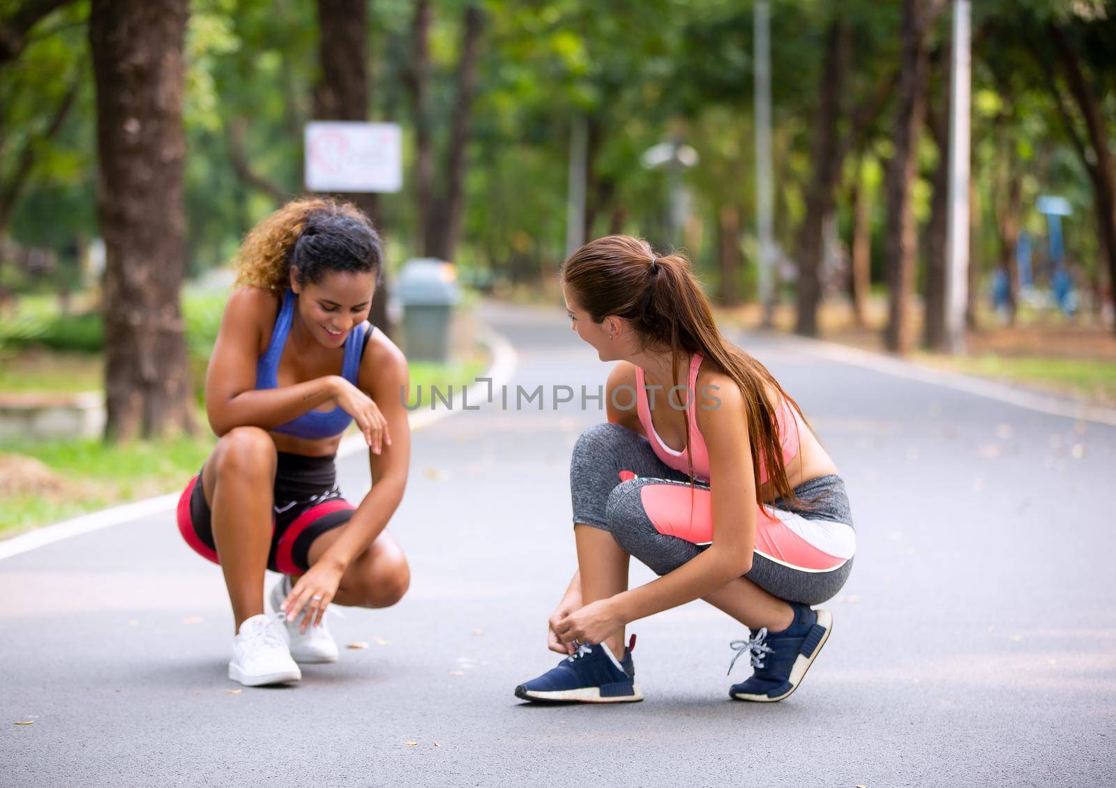 Happy young curvy women jogging together in park. Healthy girls friends running on the city street to lose weight.