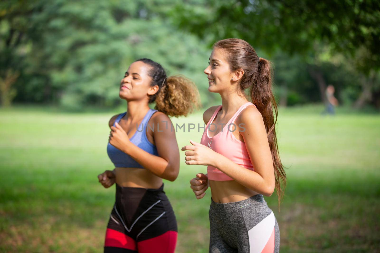 Happy young curvy women jogging together in park. Healthy girls friends running on the city street to lose weight. by chuanchai