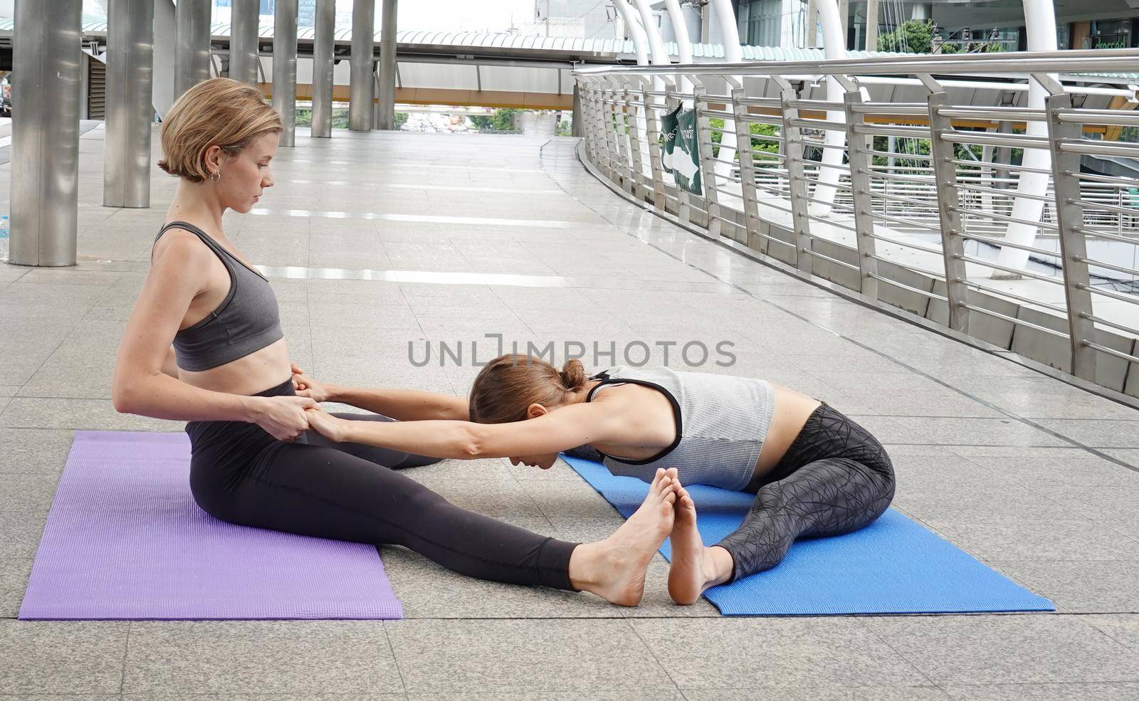 Young attractive smiling woman practicing yoga pose, working out, wearing sportswear pants, bra, full length, outdoor.