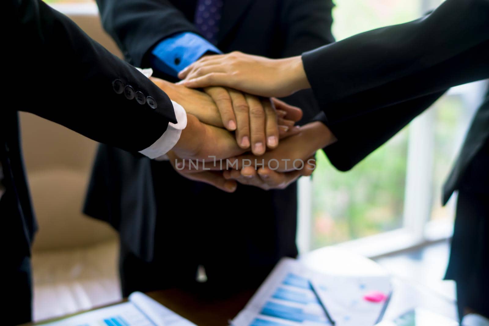 business team working at trendy loft office. Young mixed race group of people puts palm together on the centre. Teamwork of happy guys, colleagues. by chuanchai