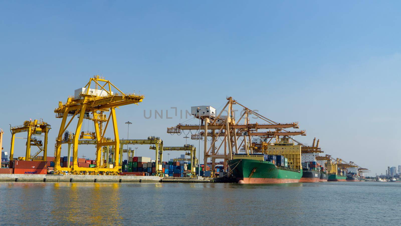 Logistics and transportation of Container Cargo ship and Cargo plane with working crane bridge in shipyard at sunrise, logistic import export and transport industry background by chuanchai