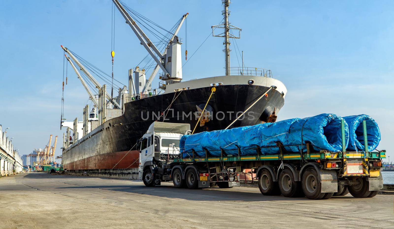 Logistics and transportation of Container Cargo ship and Cargo plane with working crane bridge in shipyard at sunrise, logistic import export and transport industry background by chuanchai