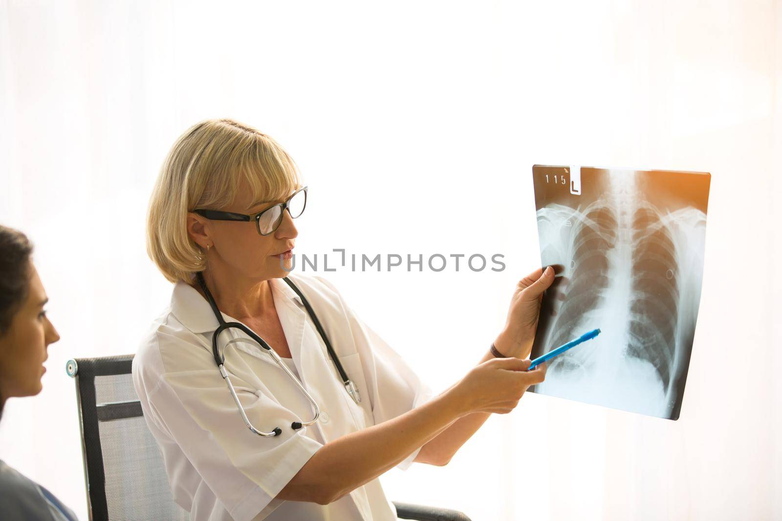 Doctor explaining lungs x-ray to women patient in clinic or Doctor in the office examining an x-ray and discussing with a patient