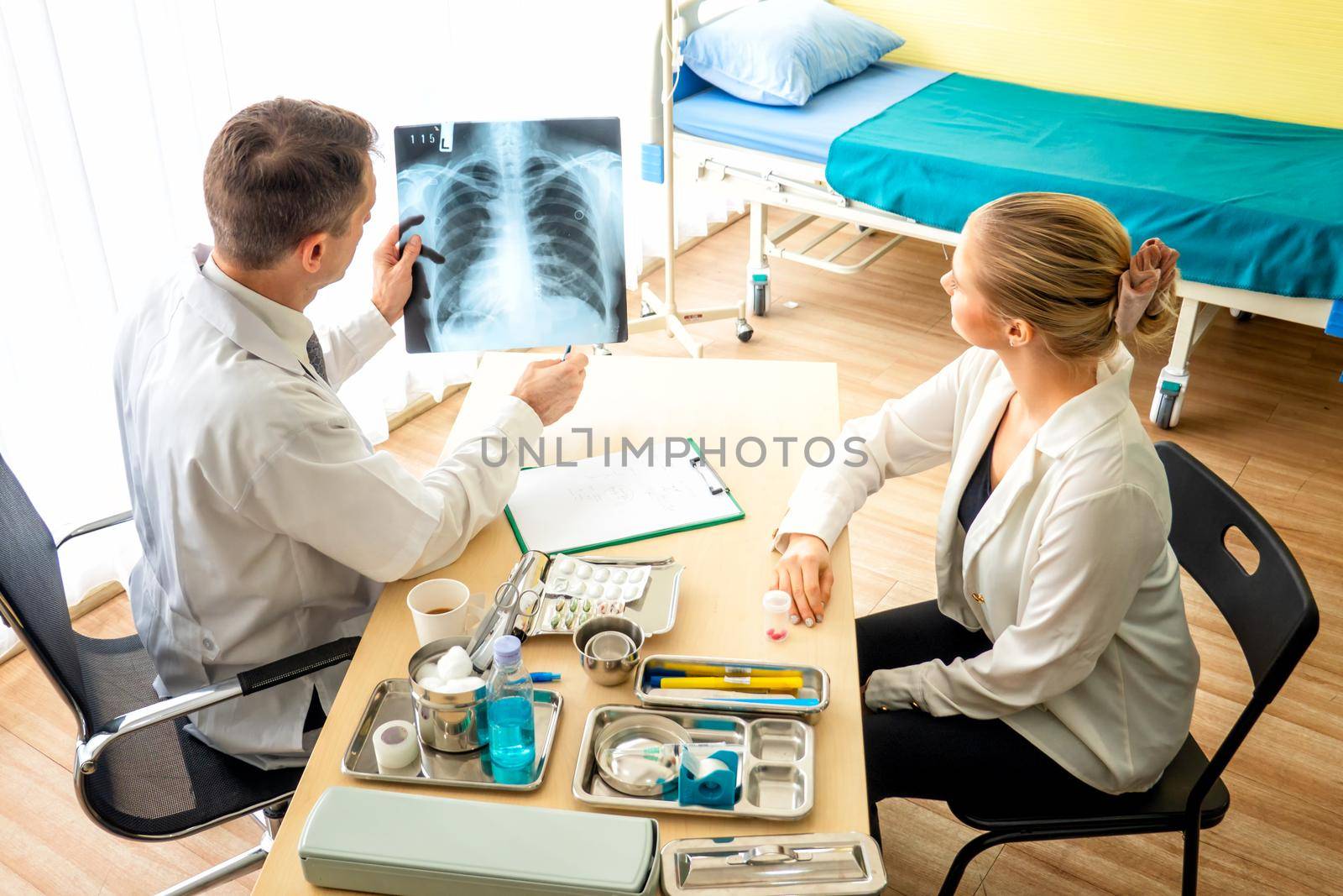 Doctor explaining lungs x-ray to women patient in clinic or Doctor in the office examining an x-ray and discussing with a patient