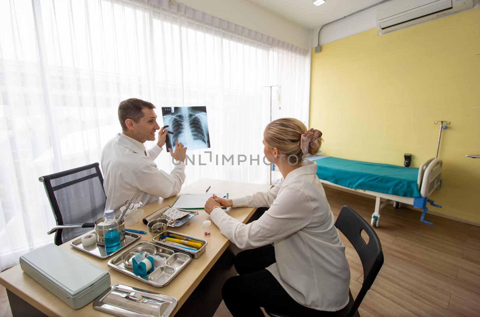 Doctor explaining lungs x-ray to women patient in clinic or Doctor in the office examining an x-ray and discussing with a patient