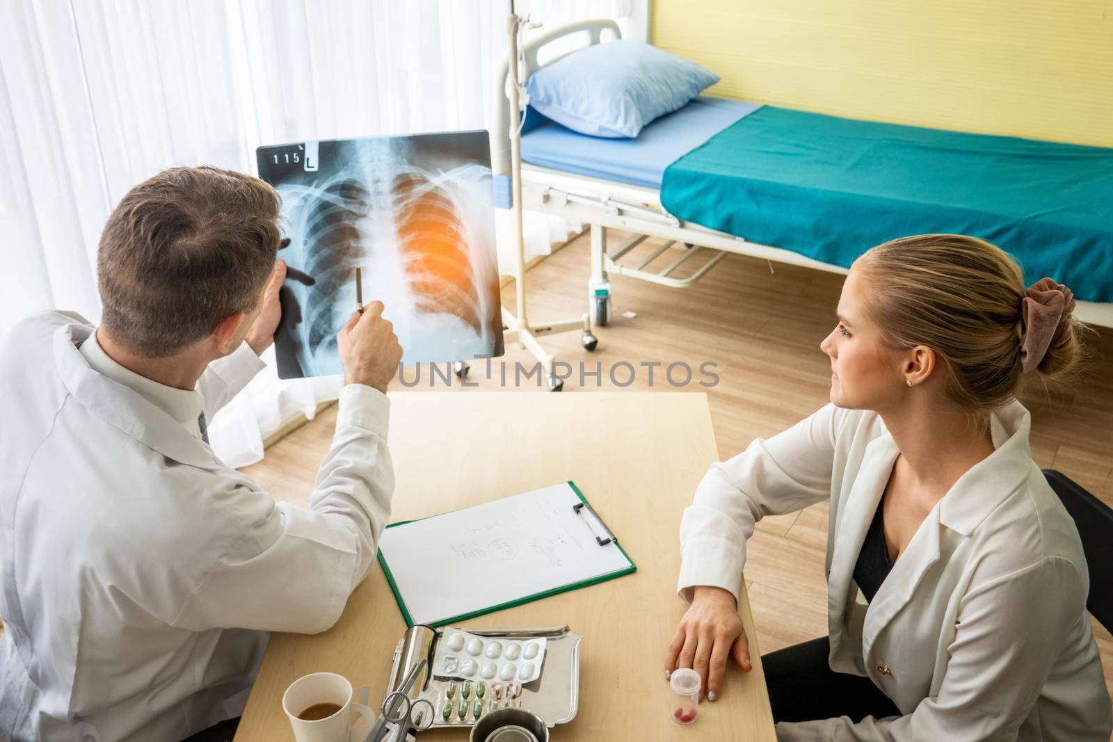 Doctor explaining lungs x-ray to women patient in clinic or Doctor in the office examining an x-ray and discussing with a patient