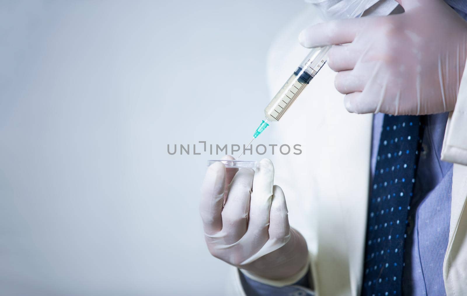 Close-Up Of Syringe Against blurred of doctor face blue Background